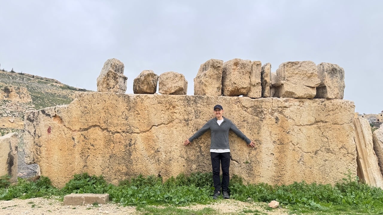 Rick with arms spread against an enormous stone block in Jordan